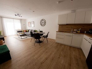 A modern kitchen with white cabinets, a wooden countertop, and a built-in dishwasher. - Come4Stay Passau - 2 Zimmer - bis zu 4 Gäste by Interhome (Passau)