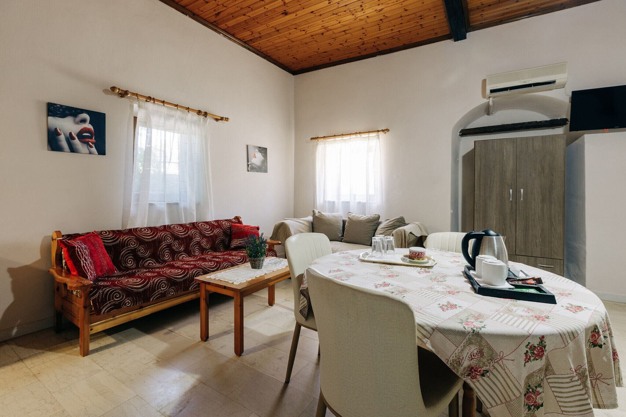 A living room with a sofa, a dining table with chairs, a coffee table, and an air conditioning unit.