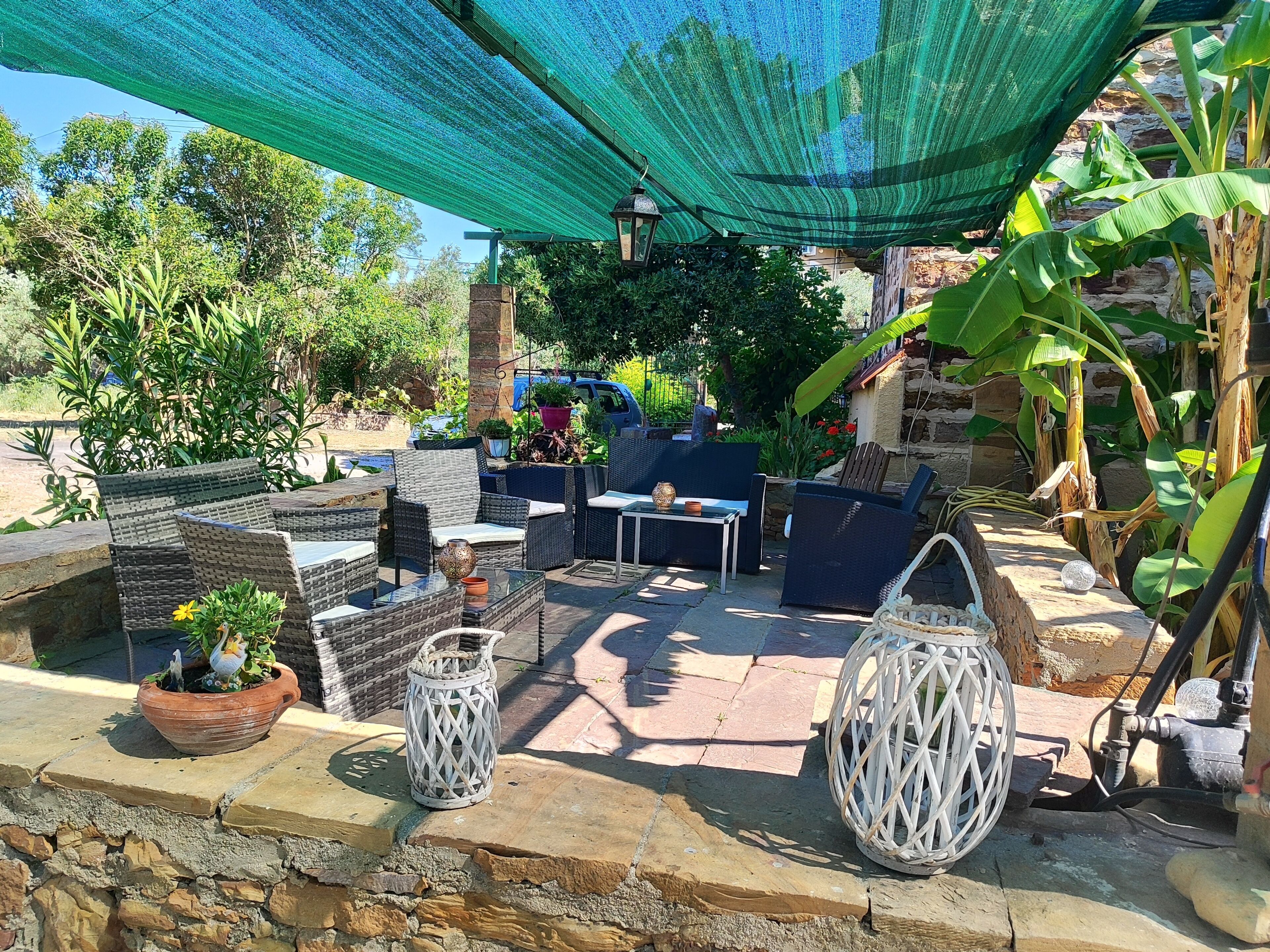 An outdoor patio with wicker furniture, potted plants, and decorative lanterns.