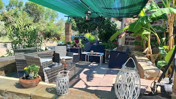 An outdoor patio with wicker furniture, potted plants, and decorative lanterns.
