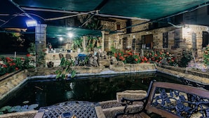 A courtyard with a pond, stone walls, and potted plants.