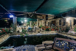 Un cortile con uno stagno, pareti in pietra e piante in vaso.