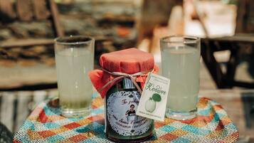 A glass table with a bottle and two glasses of a beverage, set on a colorful placemat.