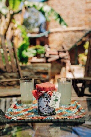 A glass table with a bottle and two glasses of a beverage, set on a colorful placemat.