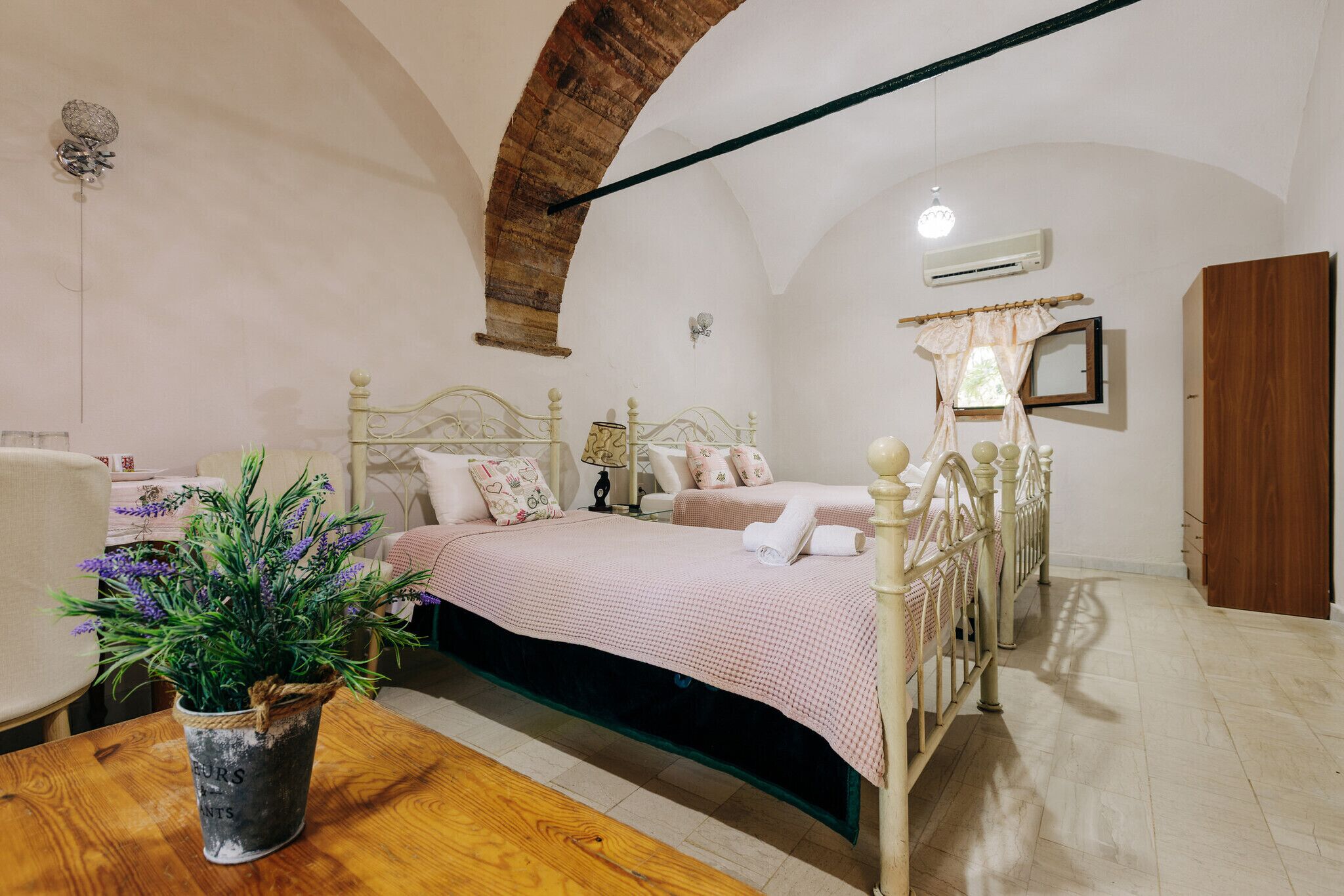 A bedroom with a four-poster bed, a wooden floor, a potted plant, and a rustic ceiling.