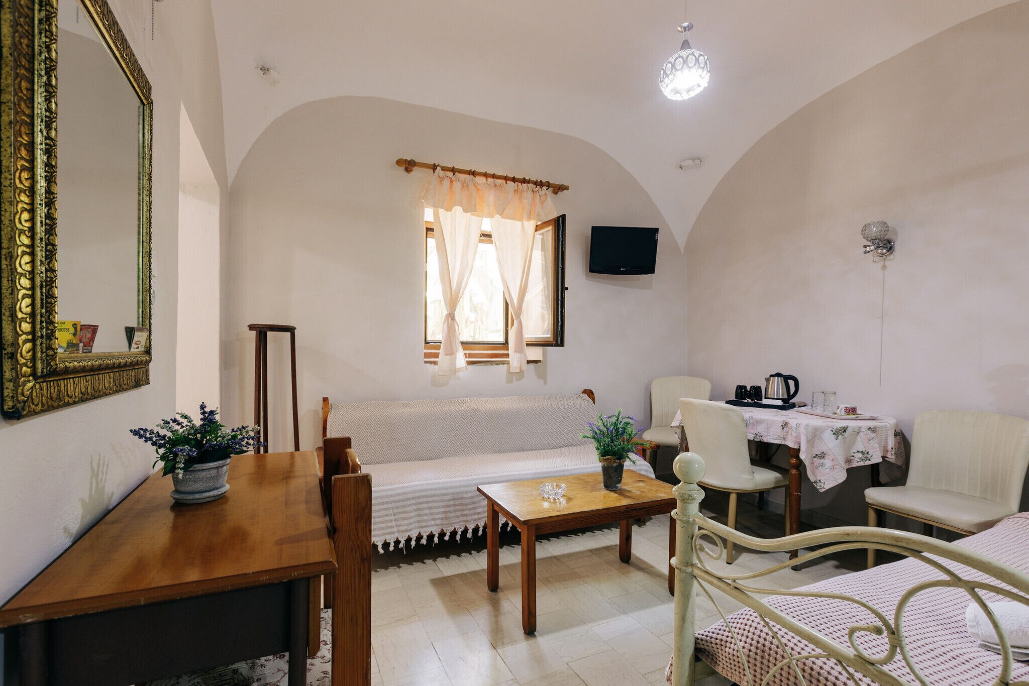 A room with a sofa, a dining table, a TV, and a bed.