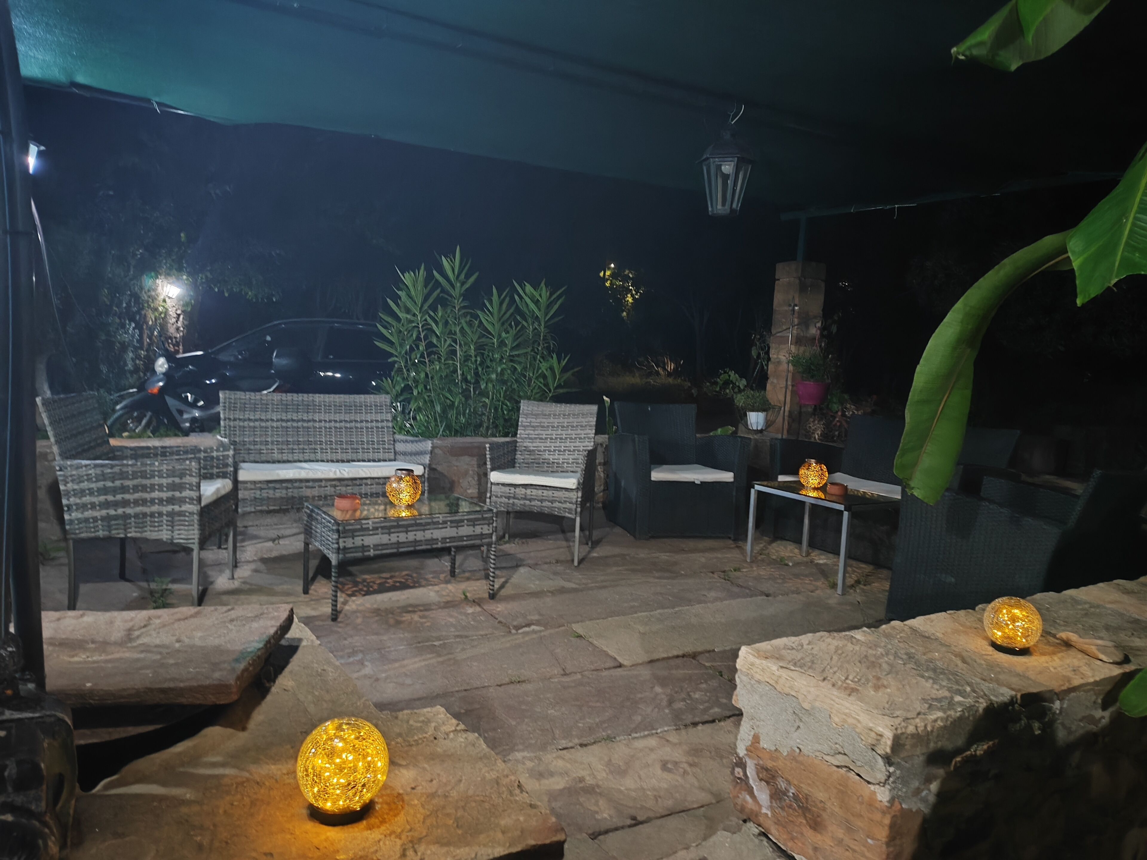 Een terras met rieten meubels, stenen tafels en decoratieve verlichting.