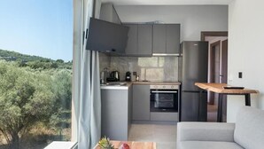 Een moderne keuken met een ingebouwde oven, een flatscreen televisie en uitzicht op bomen.