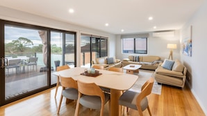 Una sala de estar moderna con comedor, ventanas amplias y un balcón.