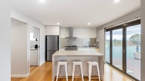 Una cocina moderna con una isla central, electrodomésticos de acero inoxidable y una puerta corrediza de vidrio a un balcón.