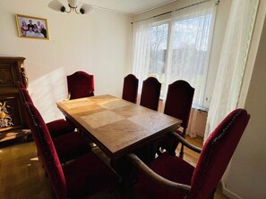 Ein Esszimmer mit einem Holztisch und sechs rot gepolsterten Stühlen.
