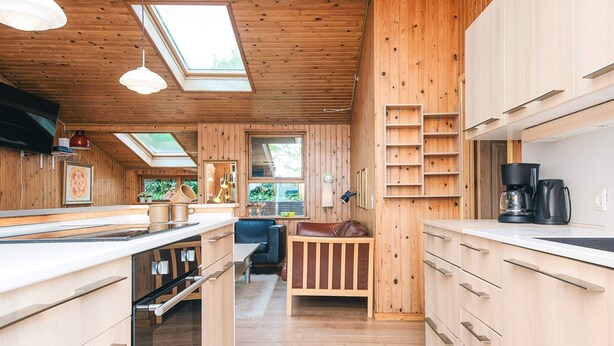 Ein Holzblockhaus im Inneren mit Küche, Essbereich und Schlafgalerie.