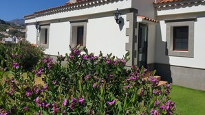 Un edificio bianco con tetto in tegole, un camino e una piccola finestra.