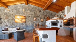 Un muro in pietra, un camino in pietra, un'area bar, mobili in vimini e un dipinto.