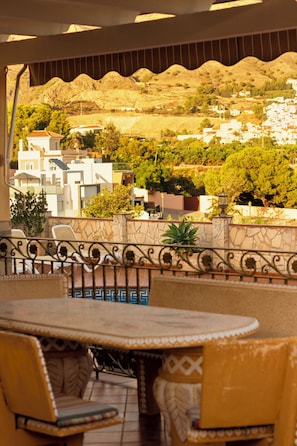 A terrace with a table and chairs, a view of a hillside with buildings, and a stone wall. - Villa Lorena with Pool, 4 bedrooms and parking (Nerja)