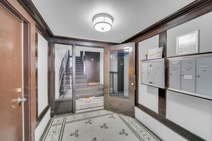 A hallway with a door leading to a stairwell, a light fixture on the ceiling, and a row of utility boxes on the wall. - Trendy and Comfortable Stay in Hyde Park (Chicago)