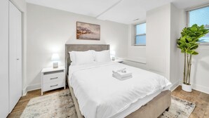 Een moderne slaapkamer met een bed, nachtkastjes, een raam en een potplant.