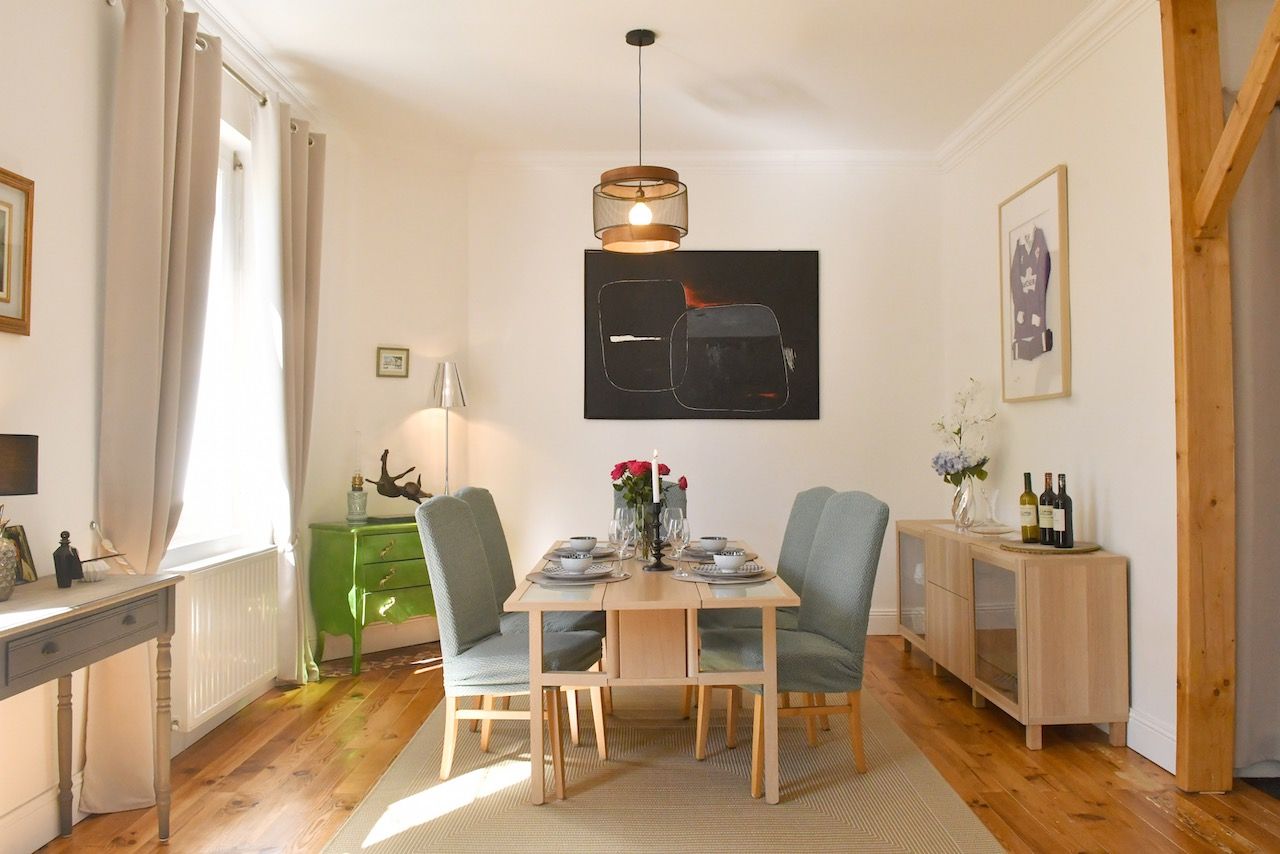 Ein Essbereich mit Holztisch, Stühlen, einer Pendelleuchte und einem gerahmten Kunstwerk an der Wand.