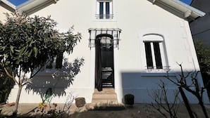 A white building with a black entrance door, two windows, and a small balcony. - Charming house with a pool and private, enclosed parking near downtown Bergerac (Bergerac)