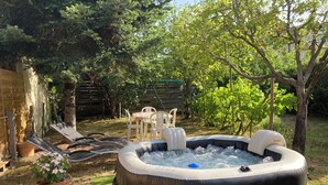 A hot tub in a backyard with a wooden fence, a table with chairs, and a potted plant. - Charming house with a pool and private, enclosed parking near downtown Bergerac (Bergerac)