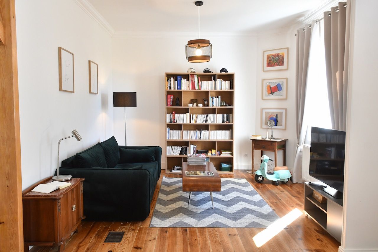 Een woonkamer met een bank, een boekenkast, een televisie en een scooter.