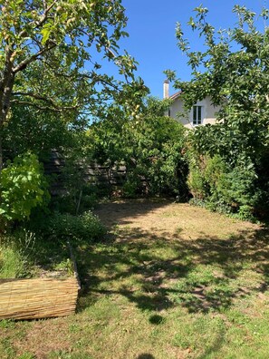A backyard with a grassy area, a wooden fence, and a house with a chimney. - Charming house with a pool and private, enclosed parking near downtown Bergerac (Bergerac)