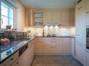 A modern kitchen with a granite countertop, wooden cabinets, and a built-in wine rack. - Haus Wick Ferienhaus, Dusche oder Bad, WC Chalet/Ferienhaus by Interhome (Klosters)