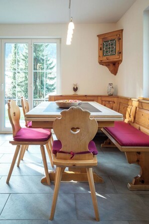 A dining area with wooden chairs and benches, a table, and a cabinet. - Haus Wick Ferienhaus, Dusche oder Bad, WC Chalet/Ferienhaus by Interhome (Klosters)