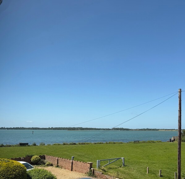A coastal view with a clear sky, a grassy area, and a body of water.