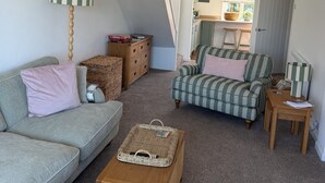 Um espaço tipo loft com teto alto, escada, cozinha compacta e uma grande janela.