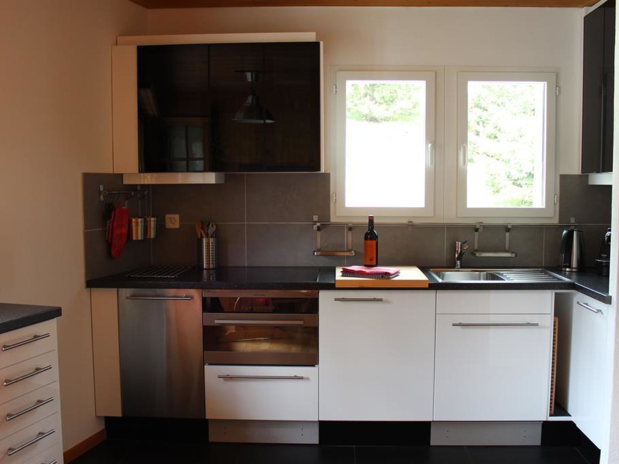 A modern kitchen with stainless steel appliances, white cabinetry, and a window providing natural light.
