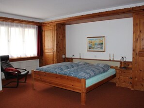 Ein Schlafzimmer mit einem hölzernen Bett, einem Sessel, einer Heizung und einem Gemälde an der Wand.