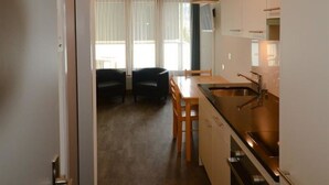 A compact kitchen with a dining area, a built-in oven, and a window with curtains. - Touring 307 Appartement/Fewo, Dusche oder Bad, WC 1-Zimmerwohnung by Interhome (Davos)