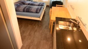 A compact room with a bed, a small table, and a kitchenette. - Touring 307 Appartement/Fewo, Dusche oder Bad, WC 1-Zimmerwohnung by Interhome (Davos)