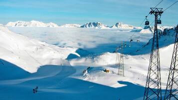 A snow-covered ski slope with ski lifts and a mountain backdrop.
