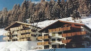 A multi-story hotel with balconies, situated on a snowy slope with trees in the background. - Efeu 201 Appartement/Fewo, Dusche oder Bad, WC 3½-Zimmerwohnung by Interhome (Davos)