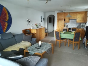 Ein Wohnzimmer mit einer Couch, einem Couchtisch und einem Essbereich mit Tisch und Stühlen.