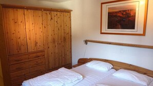 A bedroom with a wooden wardrobe, a bed with white bedding, and a framed picture on the wall. - Efeu 201 Appartement/Fewo, Dusche oder Bad, WC 3½-Zimmerwohnung by Interhome (Davos)