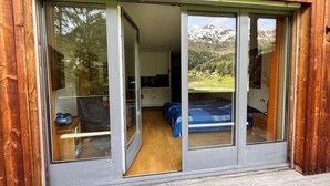 Una habitación con cama, escritorio y vistas a un paisaje montañoso a través de grandes puertas correderas de vidrio.