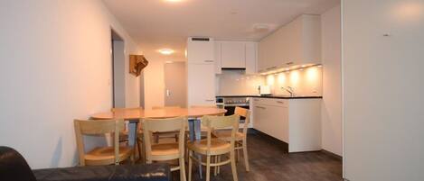 Un espacio habitable compacto con comedor, kitchenette y un sofá de cuero.