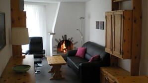 Ein Wohnzimmer mit Kamin, einer Couch, einem Sessel, einem Tisch und Holzschränken.
