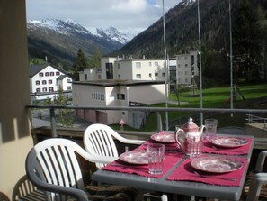 A balcony with a table set for dining, chairs, and a view of buildings and mountains. - Parsennresidenz 305 Appartement/Fewo, Dusche oder Bad, WC 2½-Zimmerwohnung by Interhome (Davos)