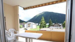Un balcon avec une table et des chaises, une vue sur une montagne et des bâtiments en arrière-plan.