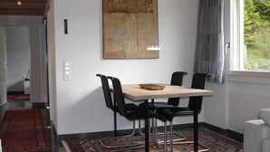 A dining area with a table, chairs, a rug, and a window with curtains. - Rex 45 Appartement/Fewo, Dusche oder Bad, WC 2-Zimmerwohnung by Interhome (Davos)
