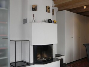 Ein modernes Wohnzimmer mit Kamin, Glastisch und einem roten Teppich.