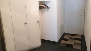 A hallway with a white wardrobe, a door with a light switch, and a checkered mat on the floor. - Talstrasse 22 App 26 Appartement/Fewo, Dusche oder Bad, WC 2½-Zimmerwohnung by Interhome (Davos)