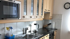 A modern kitchen with wooden cabinets, a black countertop, stainless steel appliances, and a clock on the wall. - Talstrasse 22 App 13 Appartement/Fewo, Dusche oder Bad, WC 3½-Zimmerwohnung by Interhome (Davos)