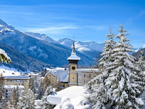 A snow-covered mountain town with a prominent church tower, surrounded by snow-laden trees and buildings. - Chesa Nova 13 Appartement/Fewo, Dusche oder Bad, WC 2 1/2-Zimmerwohnung by Interhome (Davos)
