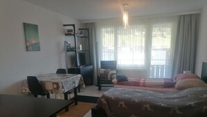 Ein Hotelzimmer mit Bett, Schreibtisch, Stuhl, Bücherregal und einem Fenster mit Vorhängen.