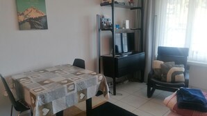 Ein Zimmer mit Bett, Schreibtisch, Stuhl, Bücherregal und einem Fenster mit Vorhängen.